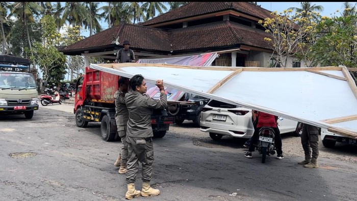 Satpol PP Tabanan saat menurunkan baliho, reklame dan banner, Selasa (27/8/2024).