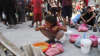 Seorang anak perempuan Gaza menyantap makanan yang didapatnya.