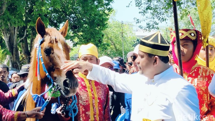 Kader Jaelani mengusap kepala kuda saat tiba di KPU Dompu, Rabu (28/8/2024). (Faruk Nickyrawi/detikBali)