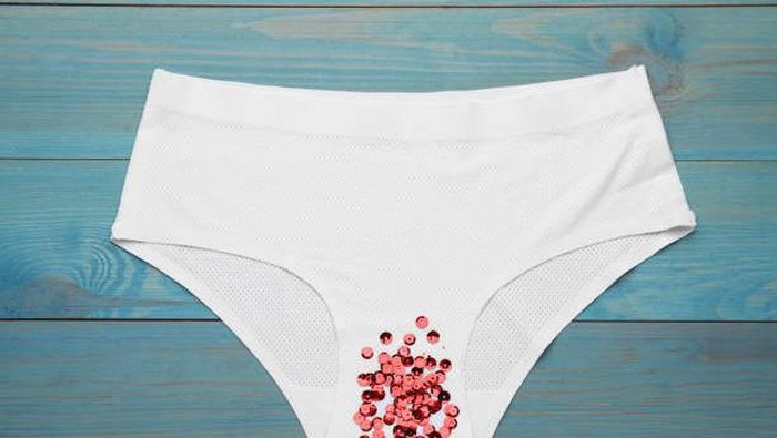 Womans panties with red sequins on turquoise wooden background, top view. Menstrual cycle