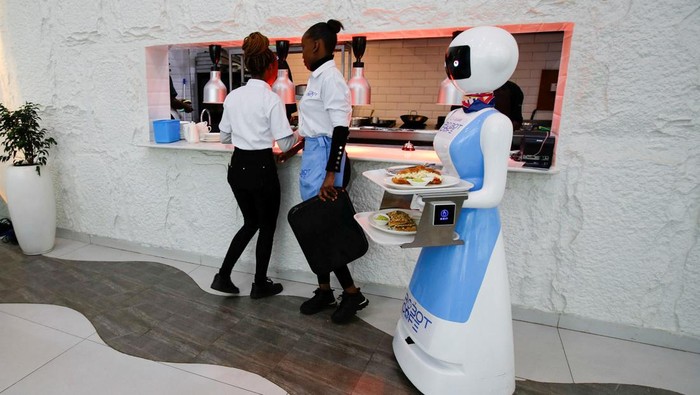 Priscilla Muite takes a photograph of Caroline Nyaga as she picks up her meal from a Robotic technology server at the Robot Cafe, the food hub featuring robots that serves customers in Nairobi, Kenya, August 22, 2024. REUTERS/Monicah Mwangi