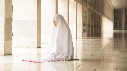 Muslim woman wearing prayer veil, praying in the mosque