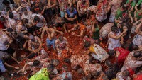 Sebelum adu makanan yang riuh itu dimulai, dan sesuai tradisi, puluhan pengunjung terlihat berusaha memanjat satu sama lain untuk meraih ham Iberia yang berharga di atas tiang yang licin. AP/Alberto Saiz 
