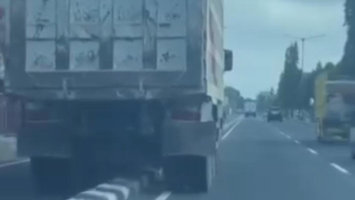 Tangkapan layar postingan truk naik ke pembatas jalan.