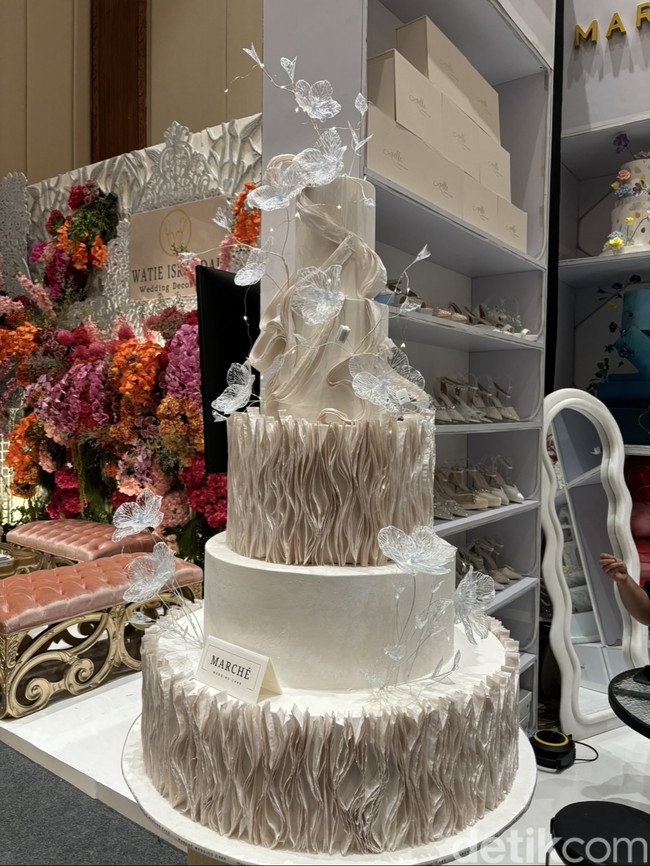 Selain warna putih, warna-warna earth tone, seperti krem juga tak kalah diminati di tahun ini. Kue pengantin dari Marche Wedding Cake itu terlihat semakin cantik dengan paduan ornamen kupu-kupu berwarna silver. Foto: Vina Oktiani/Wolipop