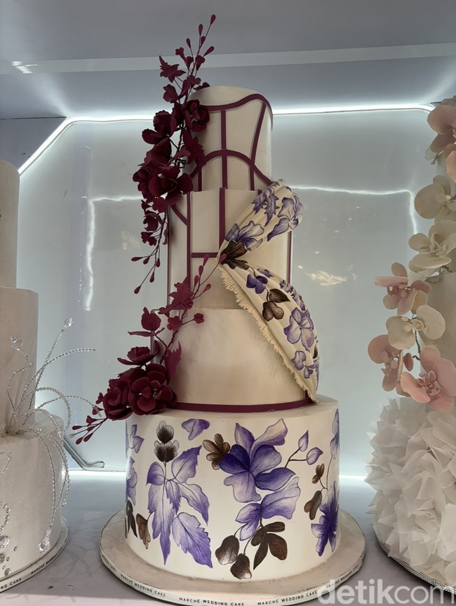 Perpaduan warna soft dan bold, seperti yang tercermin dalam kue pengantin yang satu ini juga jadi tren di tahun 2024. Kue pengantin berwarna putih tersebut terlihat semakin cantik dengan sentuhan warna marun. Foto: Vina Oktiani/Wolipop