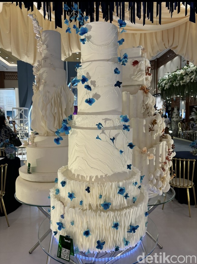 Tak hanya bermain di tekstur, kue pengantin dari SweetSalt Wedding Cake juga bisa dipermanis dengan sedikit ornamen dan warna tambahan, seperti bunga-bunga kecil berwarna biru. Foto: Vina Oktiani/Wolipop