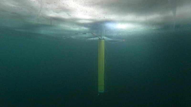 A remote camera captured an IceNode prototype deployed below the frozen surface of Lake Superior, off Michigan's Upper Peninsula, during a field test in 2022. The three thin legs of the robot's 
