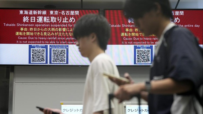 A person has a lunch box outside of the Tokaido and Sanyo Shinkansen bullet trains at Tokyo Station Friday, Aug. 30, 2024, in Tokyo, as its gate was closed due to heavy rains caused by a tropical storm. (AP Photo/Eugene Hoshiko)