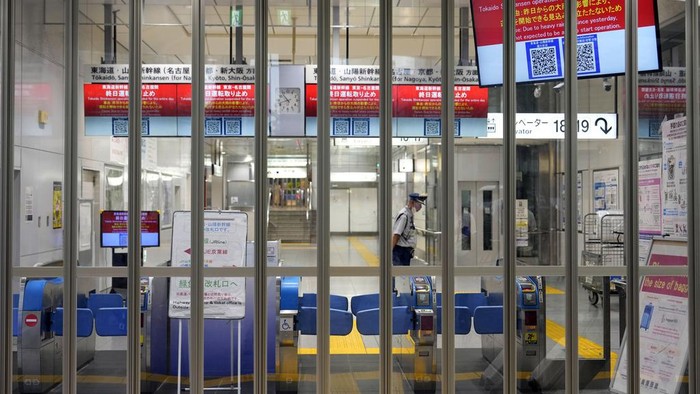 A person has a lunch box outside of the Tokaido and Sanyo Shinkansen bullet trains at Tokyo Station Friday, Aug. 30, 2024, in Tokyo, as its gate was closed due to heavy rains caused by a tropical storm. (AP Photo/Eugene Hoshiko)