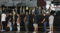 Mereka tidak membawa barang bawaan, diborgol, dan menaiki tangga pesawat secara perlahan.