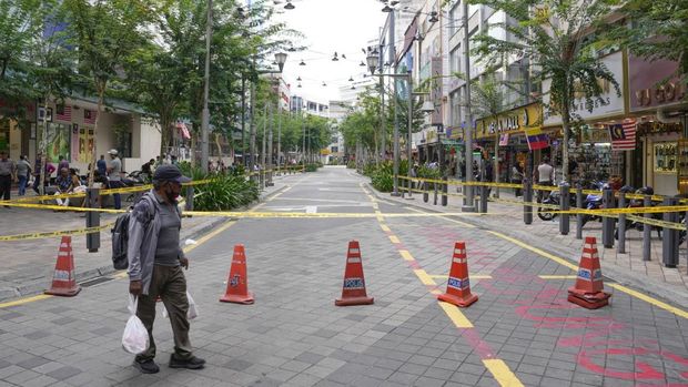 Seorang pria melintasi area yang ditutup untuk umum setelah insiden turis India terjatuh ke dalam sinkhole di area Kuala Lumpur pada 23 Agustus lalu (AP Photo/Vincent Thian)