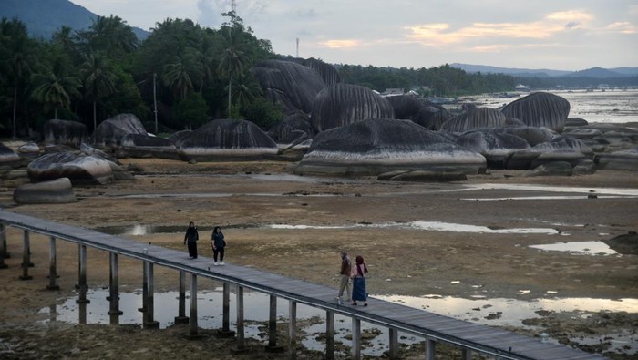 Wisatawan berjalan di jembatan kayu sepanjang 200 meter saat berwisata di Tapak Natuna, Kepulauan Riau, Kamis (29/8/2024). Wisata Tapak Natuna atau Teras Utara Indonesia merupakan lanskap alami dari bebatuan granit raksasa yang terletak di atas laut dan ditandai dengan marka penunjuk perbatasan antara delapan negara yang menjadi salah satu ikon unik Pulau Natuna. ANTARA FOTO/Arif Firmansyah/tom.