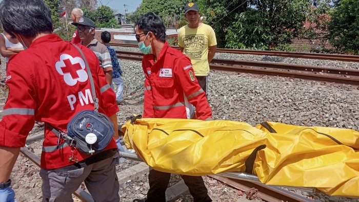 Petugas saat mengevakuasi perempuan yang tewas usai diduga bunuh diri dengan menabrakan diri ke kereta api, Jumat (30/8/2024).