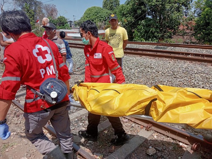 Petugas saat mengevakuasi perempuan yang tewas usai diduga bunuh diri dengan menabrakan diri ke kereta api, Jumat (30/8/2024).