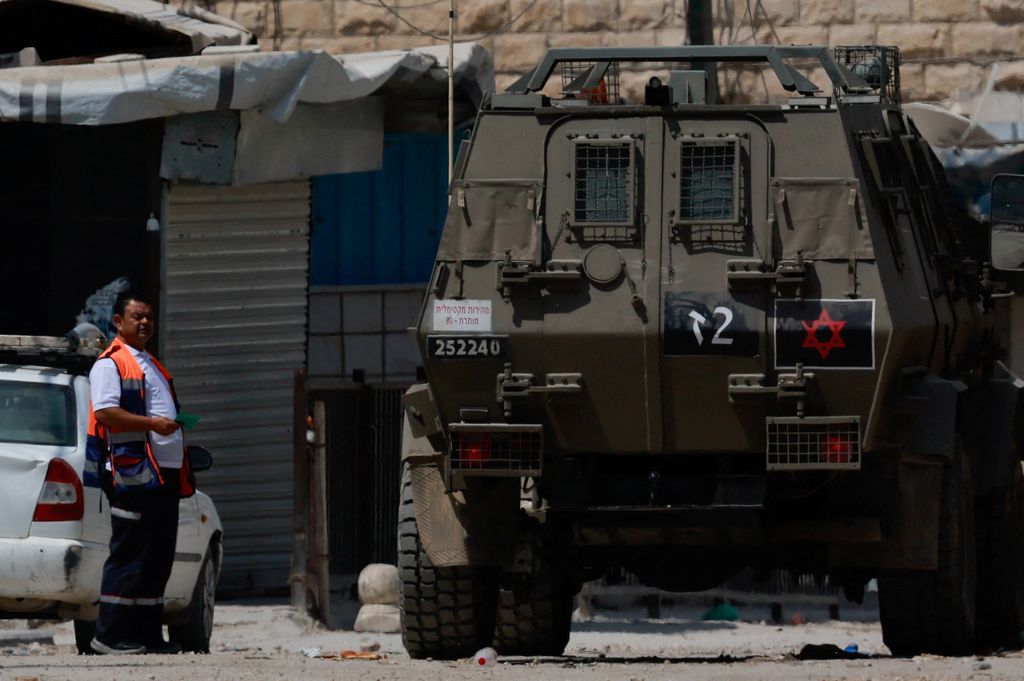 Seorang pria berdiri di samping kendaraan lapis baja selama serangan Israel di Jenin, di Tepi Barat yang diduduki Israel, 31 Agustus 2024. (REUTERS/Ammar Awad)