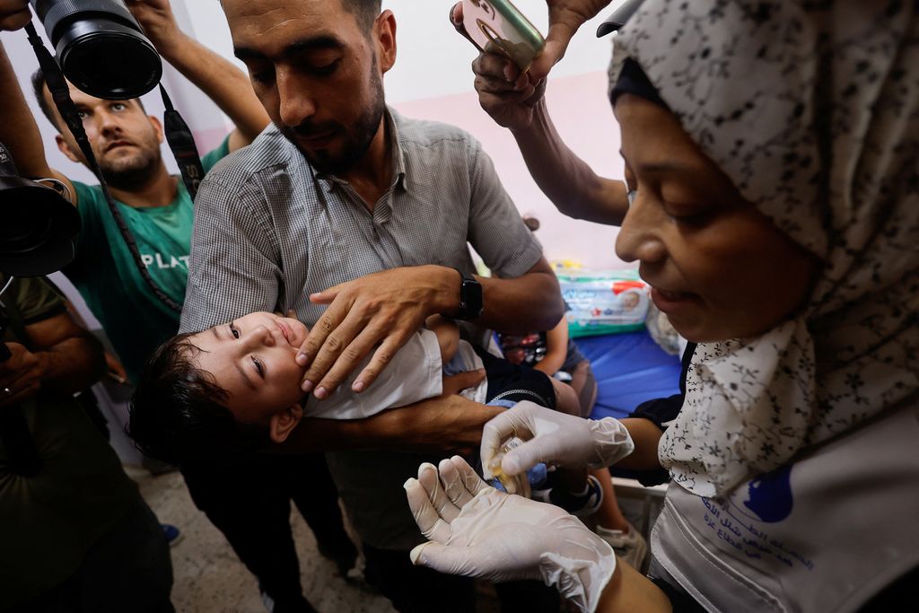 Seorang pria Palestina menggendong seorang anak, saat anak tersebut divaksinasi polio, di tengah konflik Israel-Hamas, di rumah sakit Nasser di Khan Younis di Jalur Gaza selatan, 31 Agustus 2024. (REUTERS/Mohammed Salem)