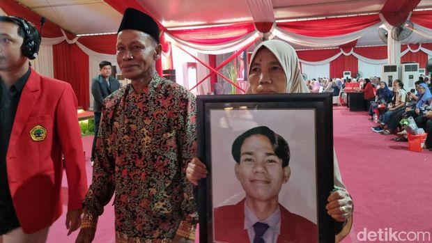 Orang tua membawa foto mendiang anaknya di acara wisuda