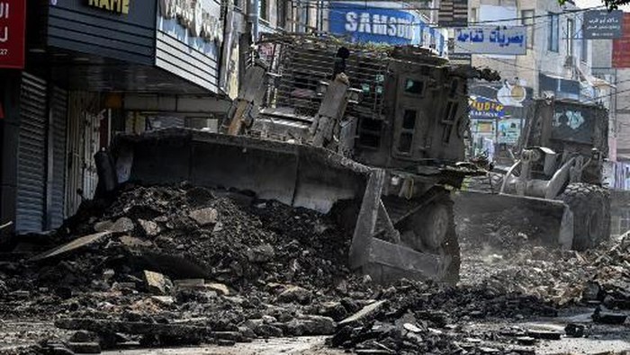 An Israeli bulldozer tears up a street as members of the press film during an Israeli raid in the occupied West Bank city of Jenin on September 1, 2024. (Photo by RONALDO SCHEMIDT / AFP)