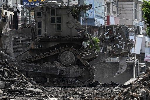 An Israeli bulldozer tears up a street as members of the press film during an Israeli raid in the occupied West Bank city of Jenin on September 1, 2024. (Photo by RONALDO SCHEMIDT / AFP)