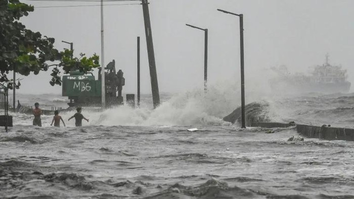 Youths wade in a storm surge along Manila Bay amid heavy rains brought by Tropical Storm Yagi in Manila on Sep 2, 2024. (Photo: AFP/JAM STA ROSA)