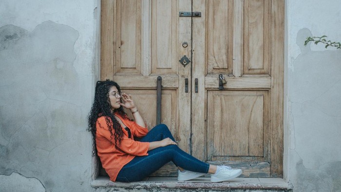Ilustrasi perempuan duduk di depan pintu