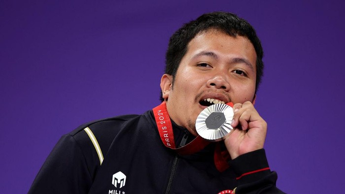 PARIS, FRANCE - SEPTEMBER 01: Silver medalist Muhammad Bintang Herlangga of Team Indonesia bites his medal on the podium at the Boccia Mens Individual - BC2 Medal Ceremony on day four of the Paris 2024 Summer Paralympic Games at South Paris Arena on September 01, 2024 in Paris, France. (Photo by Alex Slitz/Getty Images)