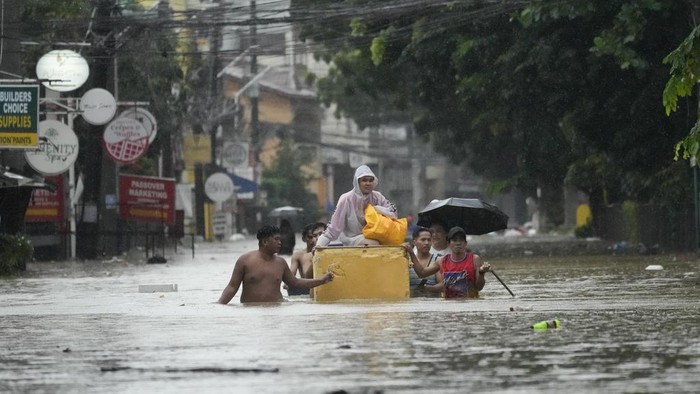 Penampakan Filipina Banjir Usai Diterjang Badai Tropis Yagi Residents use rubber paddles from a toy boat as they wade along a flooded street caused by heavy rains from Tropical Storm Yagi, on Monday, Sept. 2, 2024, in Cainta, Rizal province, Philippines. (AP Photo/Aaron Favila)