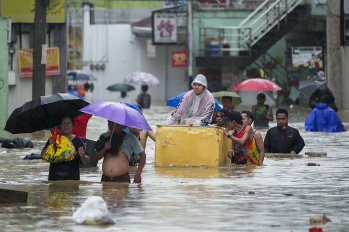 Residents use rubber paddles from a toy boat as they wade along a flooded street caused by heavy rains from Tropical Storm Yagi, on Monday, Sept. 2, 2024, in Cainta, Rizal province, Philippines. (AP Photo/Aaron Favila)