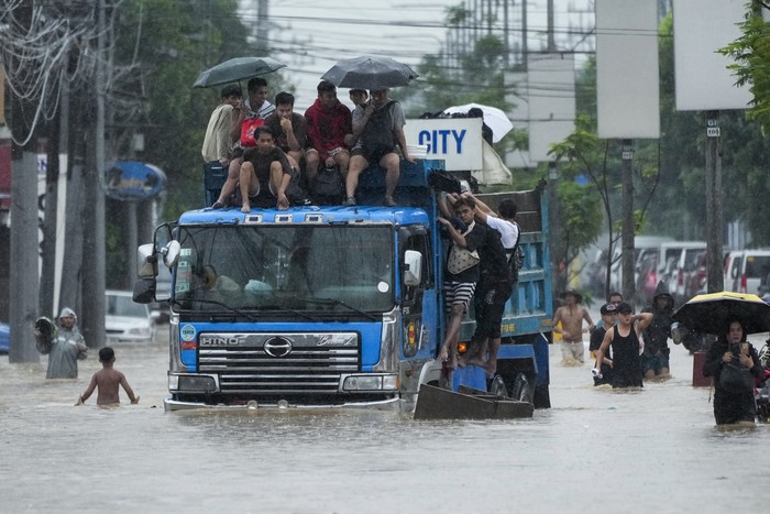 Residents use rubber paddles from a toy boat as they wade along a flooded street caused by heavy rains from Tropical Storm Yagi, on Monday, Sept. 2, 2024, in Cainta, Rizal province, Philippines. (AP Photo/Aaron Favila)