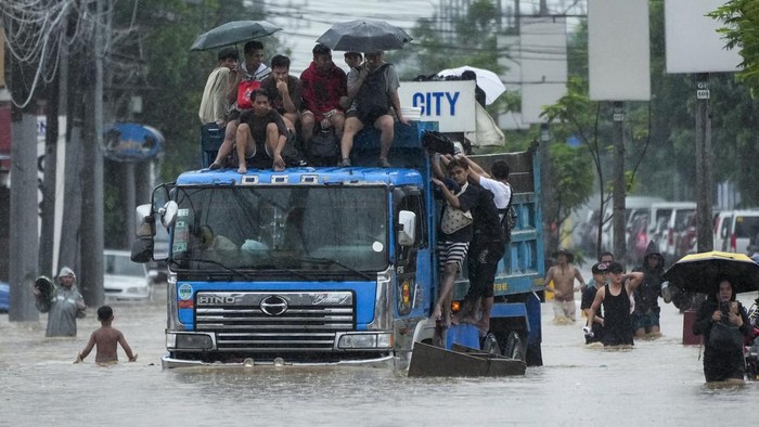 Residents use rubber paddles from a toy boat as they wade along a flooded street caused by heavy rains from Tropical Storm Yagi, on Monday, Sept. 2, 2024, in Cainta, Rizal province, Philippines. (AP Photo/Aaron Favila)