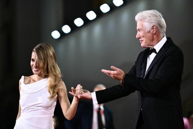 Richard Gere tak sendiri saat hadir di pemutaran perdana film Wolf’s di Festival Film Internasional Venice ke-81, Venesia, Italia, Minggu (1/9/2024). Dia membawa istri tercintanya, Alejandra Silva. Foto: Marco BERTORELLO / AFP
