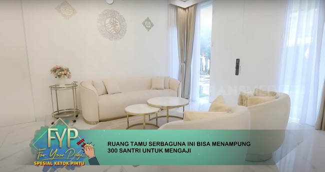 Pada sisi lain ruang tamu, terdapat sofa-sofa putih yang clean dan mempercantik ruangan. Oki Setiana Dewi menyebut ruang tamu di rumahnya terdapat dua pintu masuk untuk masuk santri perempuan dan laki-laki. Foto: dok. YouTube Trans7