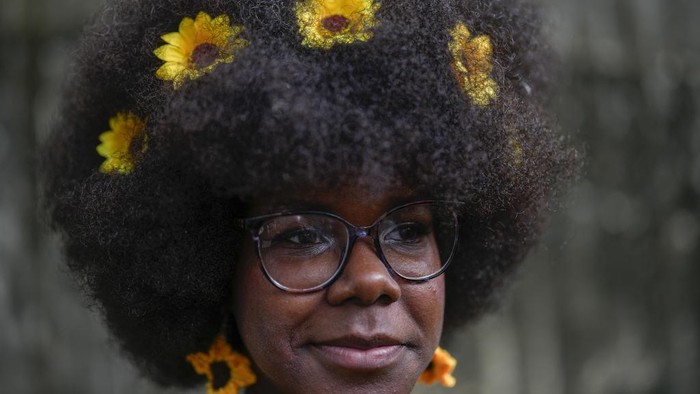 Lenggak-lenggok Peragaan Busana dan Rambut Kribo Afro di Kuba A woman with sunflowers in her hair waits to walk the runway at a fashion show of Afro hairstyles in Havana, Cuba, Saturday, Aug. 31, 2024. (AP Photo/Ramon Espinosa)