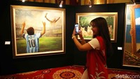 Pengunjung mengabadikan lukisan yang dipamerkan.