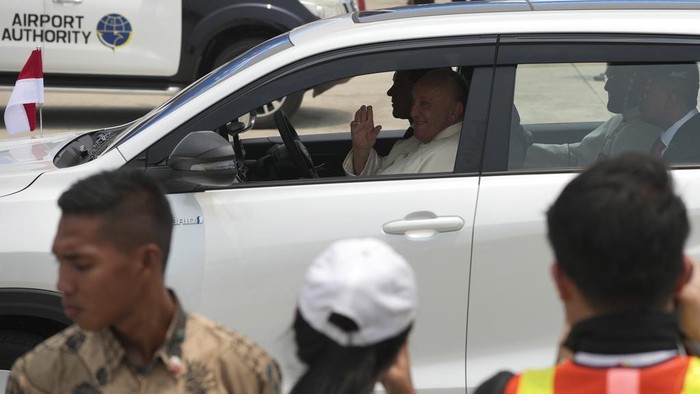 Pope Francis leaves in a car, waves after landing at Soekarno-Hatta International Airport in Tangerang on the outskirts of Jakarta, Indonesia, Tuesday, Sept. 3, 2024. (AP Photo/Achmad Ibrahim)