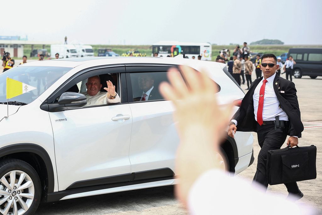 Paus Fransiskus melambai dari mobil setelah tiba di Bandara Internasional Soekarno-Hatta di Tangerang dekat Jakarta, Indonesia, 3 September 2024. (REUTERS/Guglielmo Mangiapane)