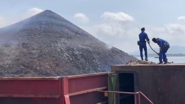 Petugas berusaha memadamkan api di kapal tongkang