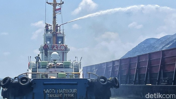 Petugas gabungan melakukan proses pemadaman terhadap kapal tongkang yang terbakar.