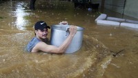 Warga terpaksa mengungsi karena ketinggian banjir telah mencapai dada orang dewasa. AP Photo/Aaron Favila.