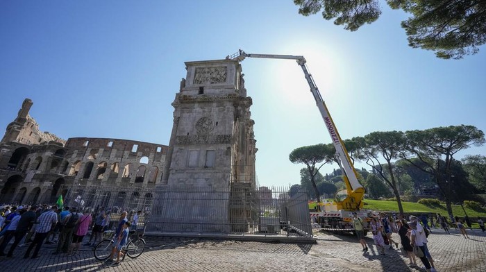 Duh, Bangunan Romawi Kuno di Italia Rusak Disambar Petir A tourist takes photos of the 315 A.D Arch of Constantine, near the Colosseum, in Rome, Wednesday, Sept. 4, 2024, as workers on site with cranes gather up fragments and secure broken areas of the arch after lightning struck it during a storm Tuesday, Sept. 3, loosening fragments from the ancient Roman structure. (AP Photo/Andrew Medichini)