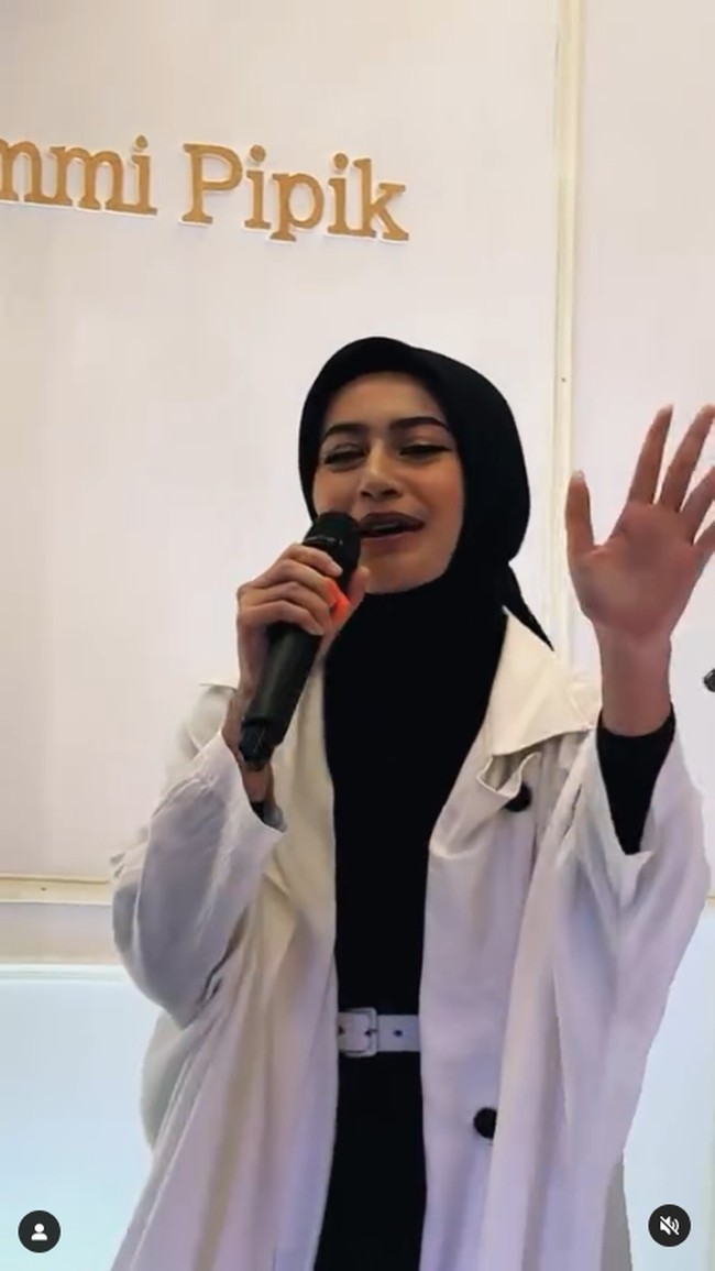 Dalam video yang viral, Sintya terlihat memakai hijab segi empat warna hijab yang diikat rapi ke belakang. Ia juga memakai long outer putih dengan abaya hitam. Foto: Dok. Instagram @sintyamarisca.