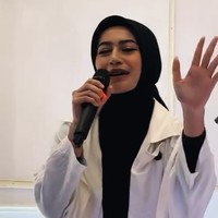 Dalam video yang viral, Sintya terlihat memakai hijab segi empat warna hijab yang diikat rapi ke belakang. Ia juga memakai long outer putih dengan abaya hitam. Foto: Dok. Instagram @sintyamarisca.