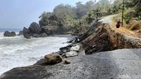 Bahu jalan amblas tergerus oleh gelombang tinggi. Puing-puing jalan raya pun berserakan di tepi pantai.
