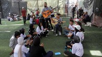 Remaja Palestina Youssef Saad memainkan oud untuk membawa kegembiraan bagi orang-orang, di tengah konflik Israel-Hamas, di kamp pengungsi Jabalia di Jalur Gaza utara pada 2 September 2024.  