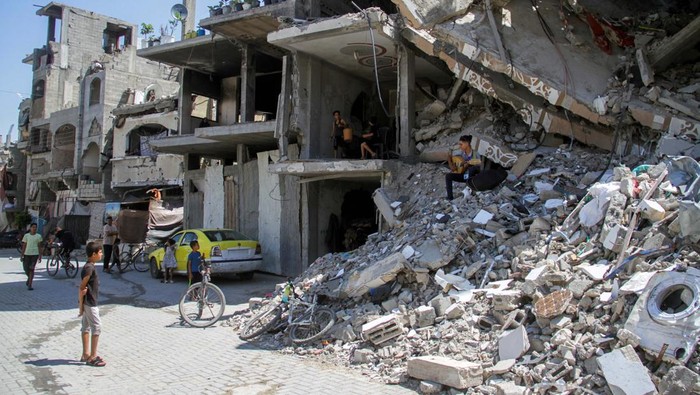 Palestinian teenager Youssef Saad sits on the rubble of his house as he plays oud to bring joy to children, amid Israel-Hamas conflict, in Jabalia refugee camp in the northern Gaza Strip September 2, 2024. REUTERS/Mahmoud Issa