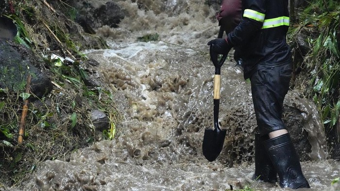 Volunteers and rescuers pull a rope to move debris during search and rescue operations for missing residents after a landslide caused by Tropical Storm Yagi, locally called Enteng, hit their village at San Luis, Antipolo city, Rizal province, Philippines on Tuesday, Sept. 3, 2024. (AP Photo/Aaron Favila)