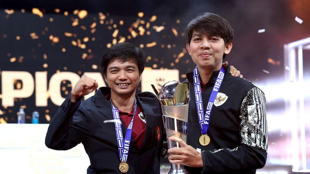 LIVERPOOL, ENGLAND - SEPTEMBER 01: Ichsan Rahmat Taufiq (miracle), Manager of Indonesia and Budi Muhamad Manar Hidayat (wednesday), Assistant Manager of Indonesia, pose for a photo with the FIFAe World Cup trophy after beating Sven Goly (Svonn), Manager of Germany and Tery Whenett (FMZweierkette), Assistant Manager of Germany (not pictured), to win the final on Day Four of the FIFAe World Cup™ featuring Football Manager at the Exhibition Centre Liverpool on September 01, 2024 in Liverpool, England. (Photo by Alex Livesey - FIFA/FIFA via Getty Images)