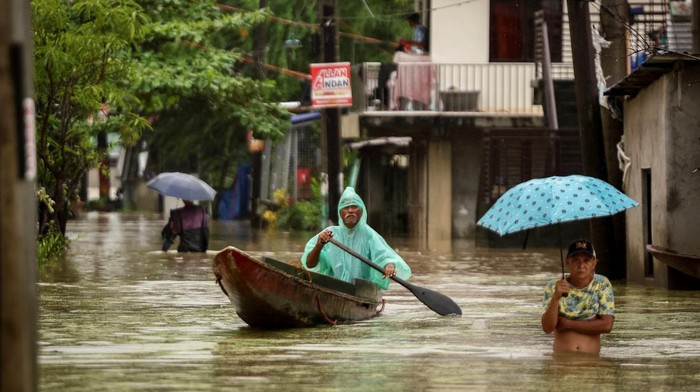 Aktivitas Warga Filipina Dikala Banjir Melanda A man wades through floodwaters with a fishing boat carrying furniture as it rains during Tropical Storm Yagi, locally known as Enteng in Apalit, Pampanga, Philippines, September 5, 2024. REUTERS/Eloisa Lopez