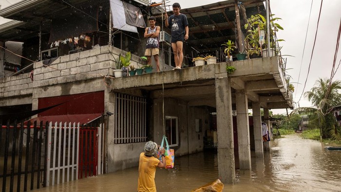 A man wades through floodwaters with a fishing boat carrying furniture as it rains during Tropical Storm Yagi, locally known as Enteng in Apalit, Pampanga, Philippines, September 5, 2024. REUTERS/Eloisa Lopez